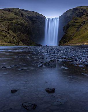 A person standing in front of Skgafoss waterfall in Iceland, Europe